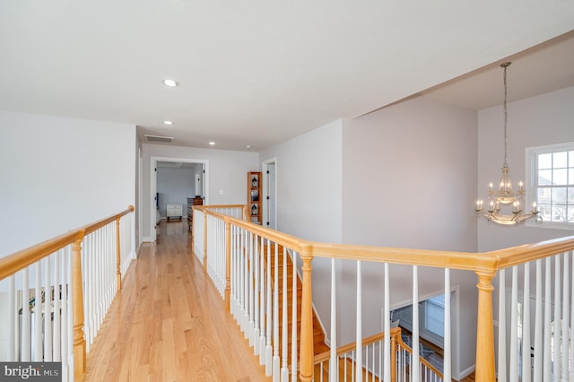 hall with visible vents, a chandelier, light wood-type flooring, an upstairs landing, and recessed lighting