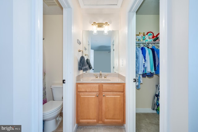 bathroom featuring a spacious closet, visible vents, toilet, and vanity