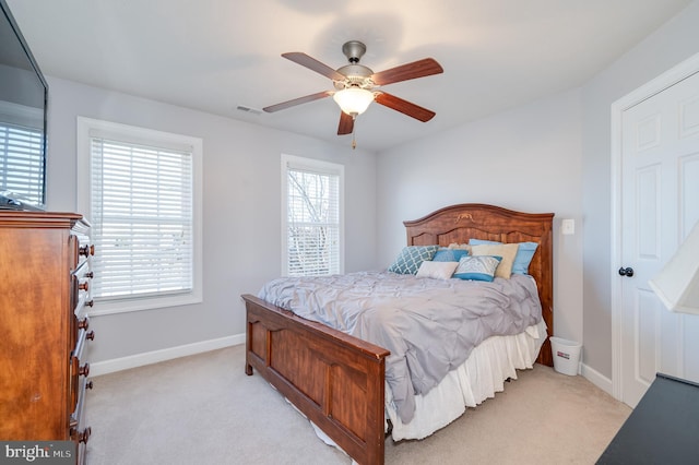 bedroom with ceiling fan, visible vents, baseboards, and light carpet