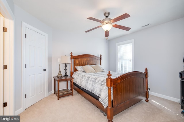 bedroom featuring visible vents, light colored carpet, baseboards, and ceiling fan