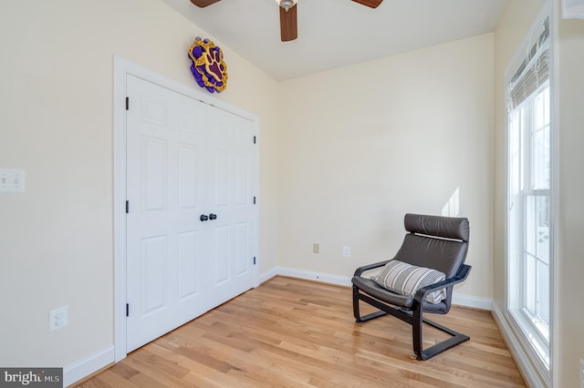 living area featuring light wood-type flooring, plenty of natural light, baseboards, and a ceiling fan