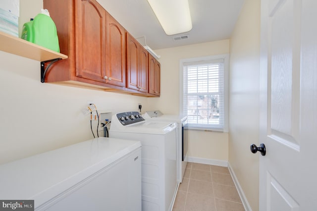 clothes washing area with light tile patterned floors, visible vents, baseboards, cabinet space, and separate washer and dryer