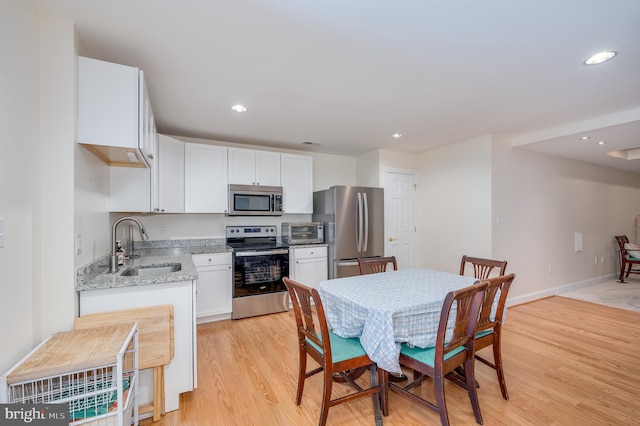 kitchen featuring a sink, light stone counters, appliances with stainless steel finishes, and white cabinetry