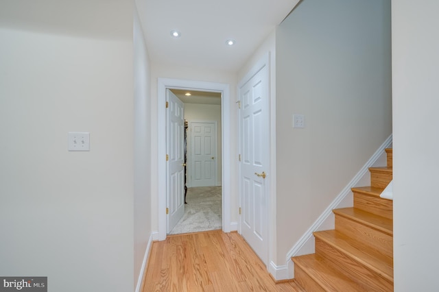 hall with stairs, recessed lighting, light wood-style floors, and baseboards