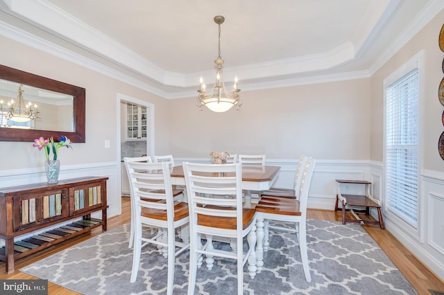 dining area featuring a notable chandelier, wainscoting, and light wood-style floors