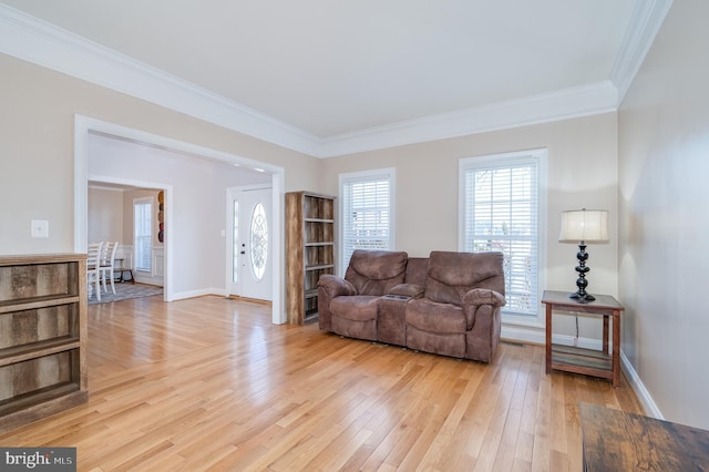 living area with baseboards, light wood-style floors, and crown molding