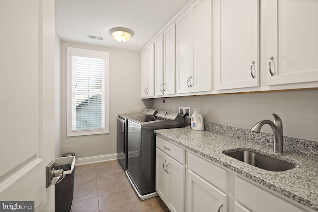 washroom with light tile patterned floors, visible vents, cabinet space, a sink, and independent washer and dryer