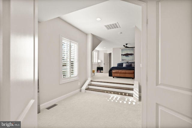 corridor with carpet, visible vents, and baseboards