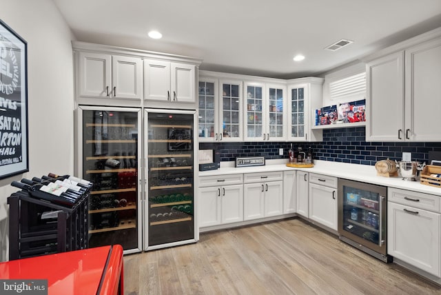 kitchen with beverage cooler, visible vents, light countertops, and light wood-type flooring