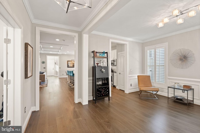 interior space featuring a wainscoted wall, a chandelier, dark wood finished floors, and ornamental molding