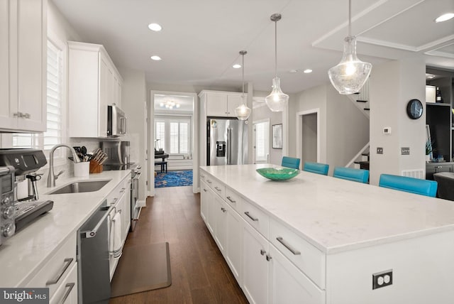 kitchen with a sink, dark wood finished floors, a center island, white cabinetry, and stainless steel appliances