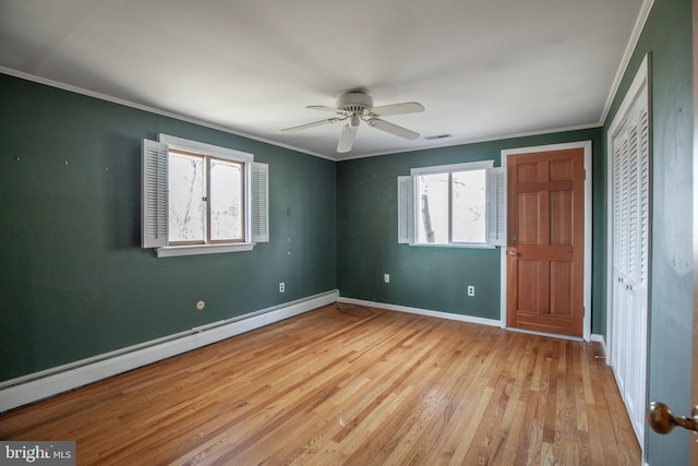 unfurnished bedroom featuring visible vents, light wood-style flooring, crown molding, baseboards, and baseboard heating