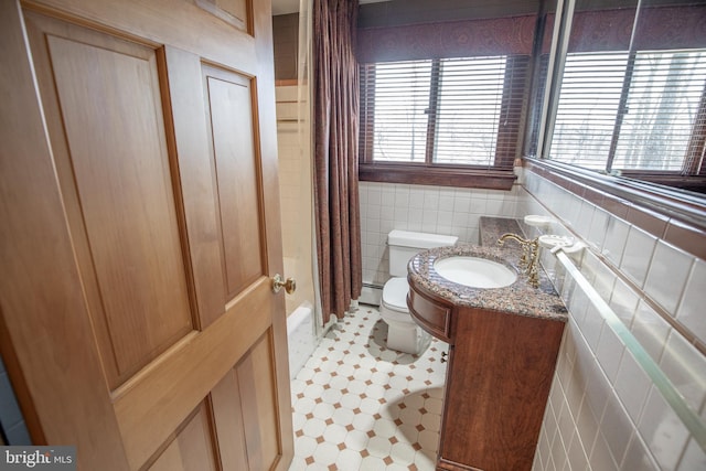 full bath with shower / bathtub combination with curtain, a sink, a baseboard heating unit, tile walls, and toilet