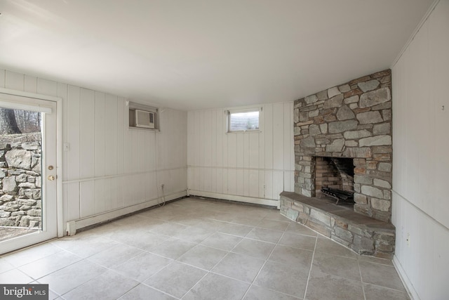 unfurnished living room featuring tile patterned flooring, baseboard heating, a fireplace, and a wall mounted air conditioner