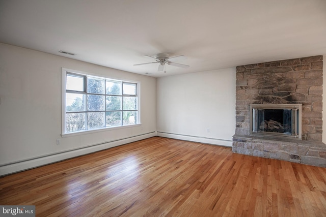 unfurnished living room with visible vents, a baseboard heating unit, a fireplace, wood finished floors, and a ceiling fan