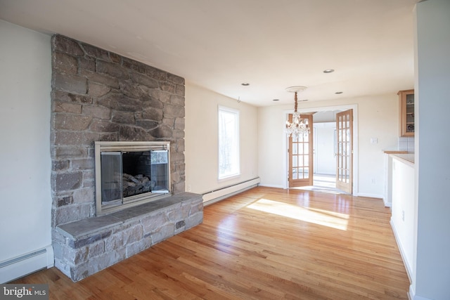 unfurnished living room featuring a baseboard heating unit, a stone fireplace, light wood finished floors, a baseboard radiator, and baseboards