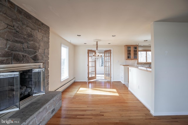 unfurnished living room featuring light wood-style flooring, a fireplace, baseboards, and baseboard heating