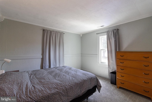 bedroom featuring crown molding, light colored carpet, visible vents, and a textured wall