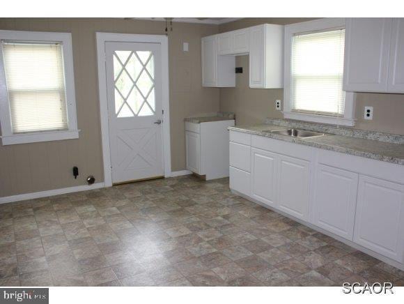 kitchen with white cabinetry, light countertops, plenty of natural light, and baseboards