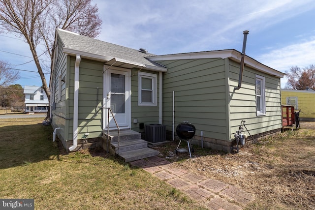 back of house with a lawn, roof with shingles, and entry steps