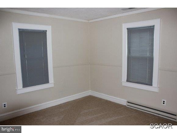 spare room with ornamental molding, carpet, baseboards, and a baseboard radiator