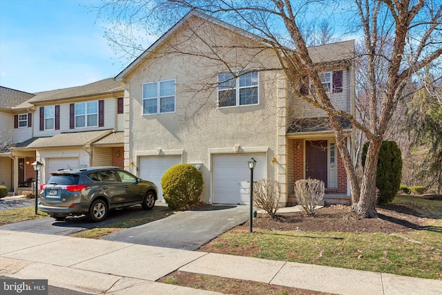 multi unit property featuring brick siding, stucco siding, an attached garage, and driveway