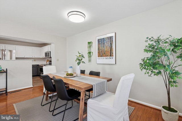 dining area featuring wood finished floors, visible vents, and baseboards