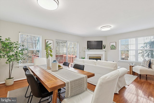 dining space with baseboards, wood finished floors, and a fireplace