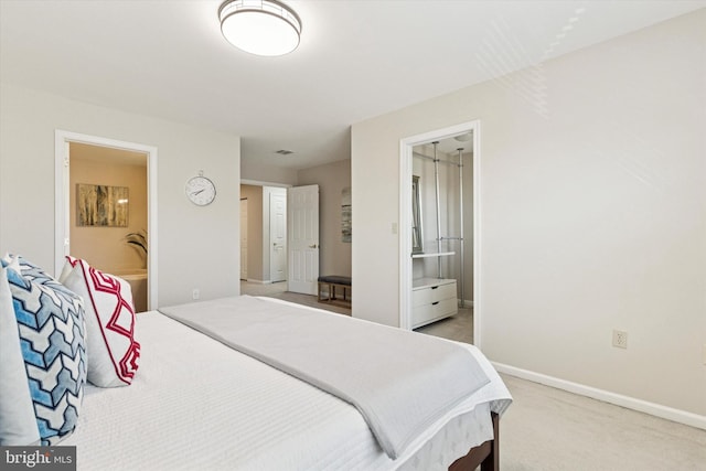 bedroom with light carpet, ensuite bath, and baseboards