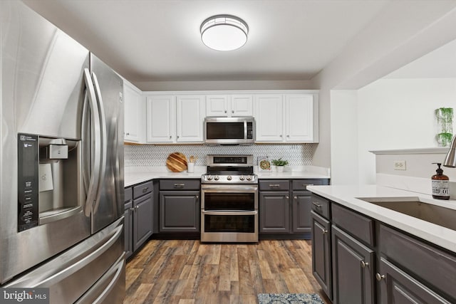 kitchen with dark wood finished floors, gray cabinets, light countertops, white cabinets, and appliances with stainless steel finishes