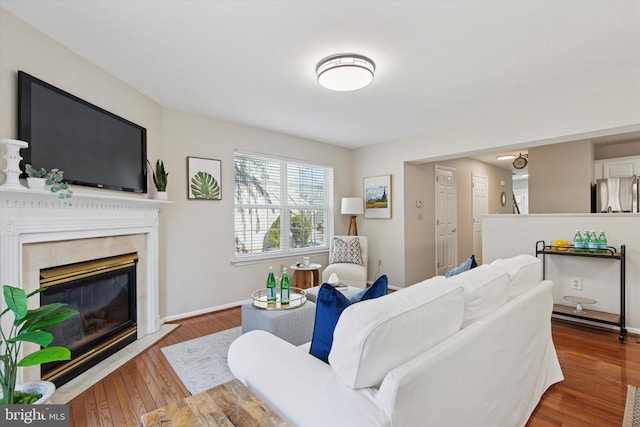 living room with a fireplace, baseboards, and wood finished floors