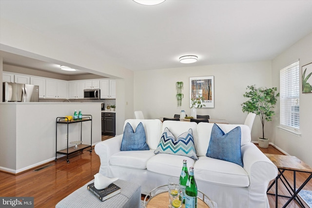 living area with visible vents, baseboards, and wood finished floors