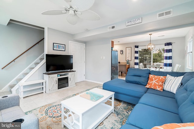 living area with stairs, ceiling fan with notable chandelier, visible vents, and baseboards