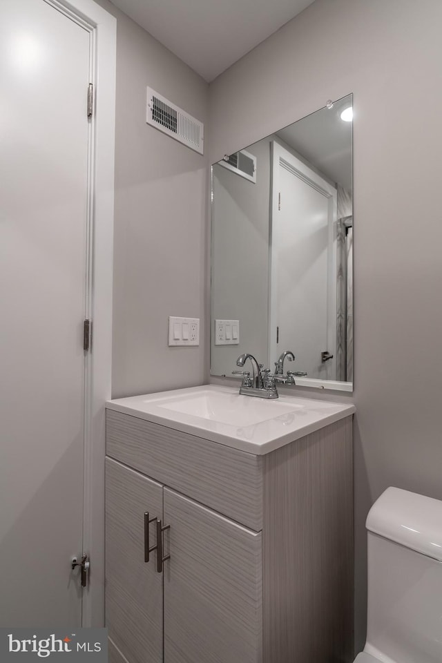 bathroom with visible vents, toilet, and vanity