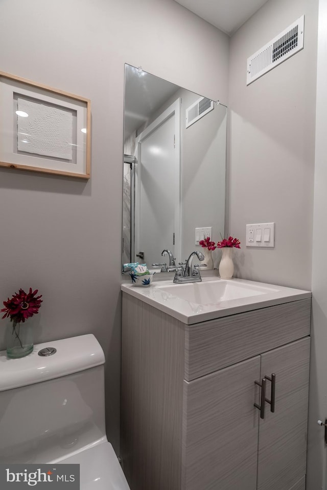 bathroom featuring vanity, toilet, and visible vents