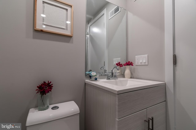 bathroom featuring visible vents, toilet, and vanity