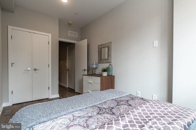 bedroom with wood finished floors, visible vents, and a closet