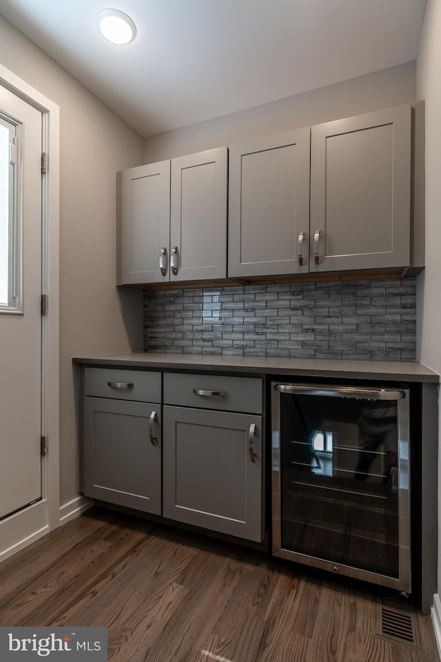 bar with wine cooler, backsplash, and dark wood-style flooring