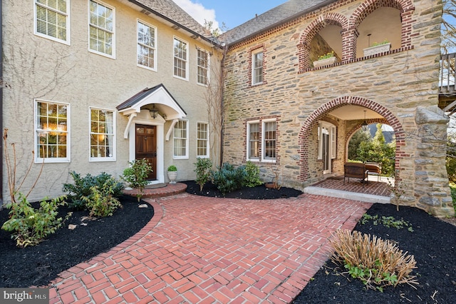 exterior space with stucco siding, stone siding, and a patio