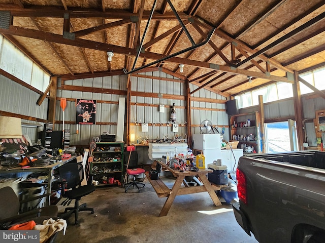 garage with a workshop area, metal wall, and freestanding refrigerator