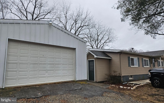 exterior space with an outbuilding, a garage, and roof with shingles