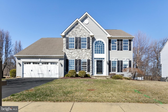 view of front of home with a shingled roof, a front yard, a garage, stone siding, and driveway