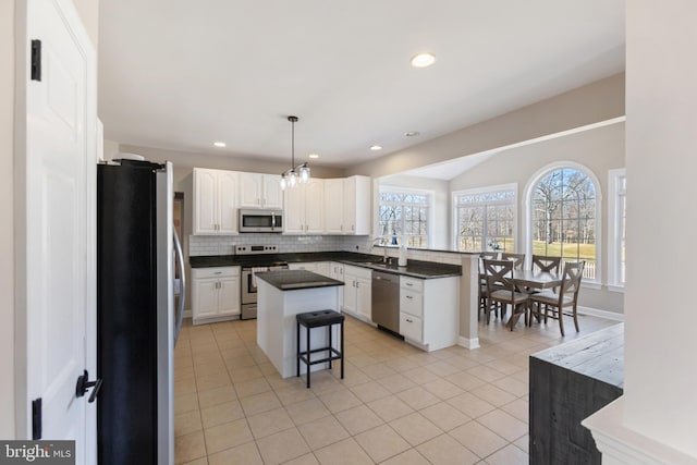 kitchen featuring a sink, tasteful backsplash, dark countertops, stainless steel appliances, and a peninsula