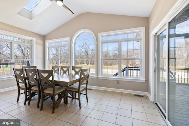 dining area featuring vaulted ceiling with skylight, light tile patterned floors, visible vents, and baseboards