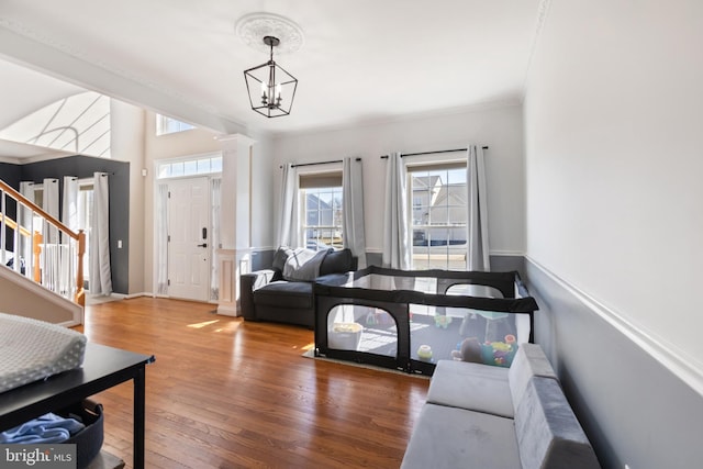 living room with crown molding, stairs, an inviting chandelier, and hardwood / wood-style floors