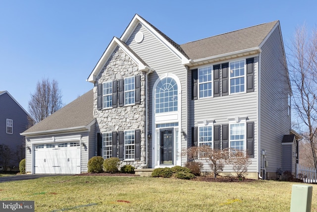 view of front facade with a shingled roof, aphalt driveway, a front yard, stone siding, and an attached garage