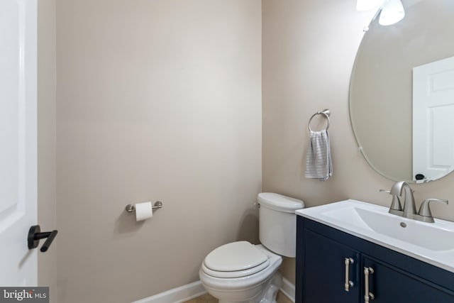 bathroom with baseboards, toilet, and vanity