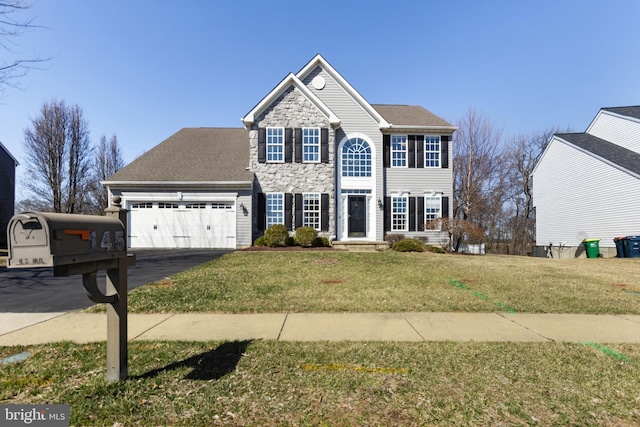 view of front of property featuring a front yard, an attached garage, stone siding, and driveway