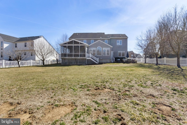 rear view of house featuring a lawn, a fenced backyard, and a sunroom