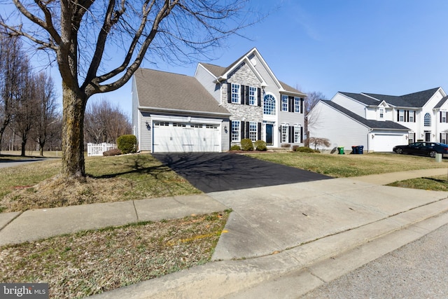 traditional-style home with a front yard, fence, a garage, and driveway